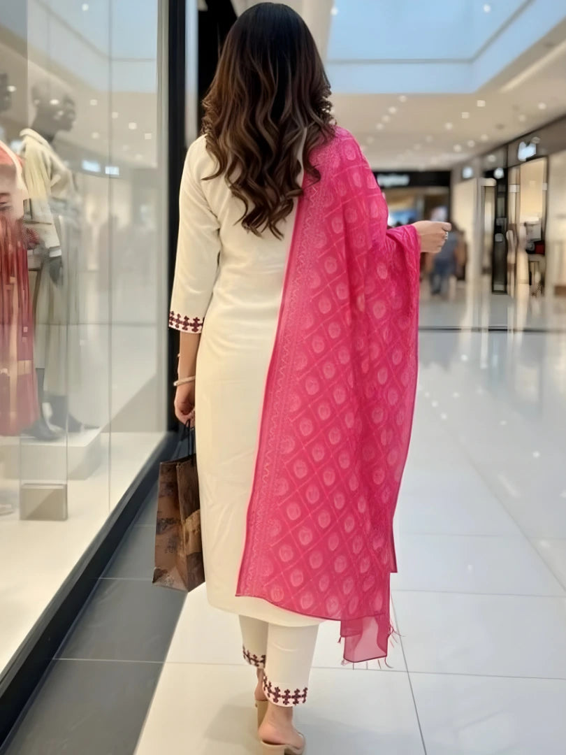 Woman in a white kurta with a pink dupatta walking in a mall.